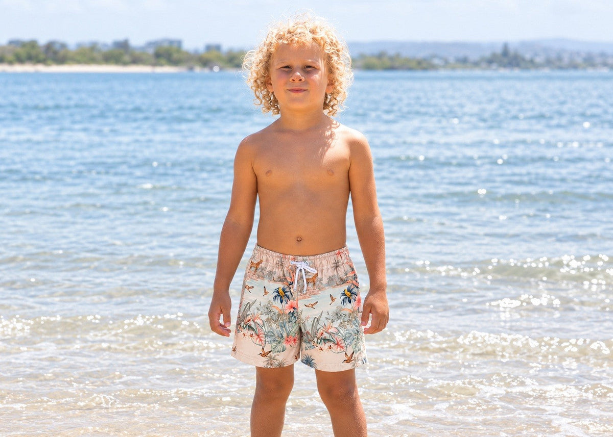 Boy on the beach wearing Wild Palms boys board shorts – Olga Valentine