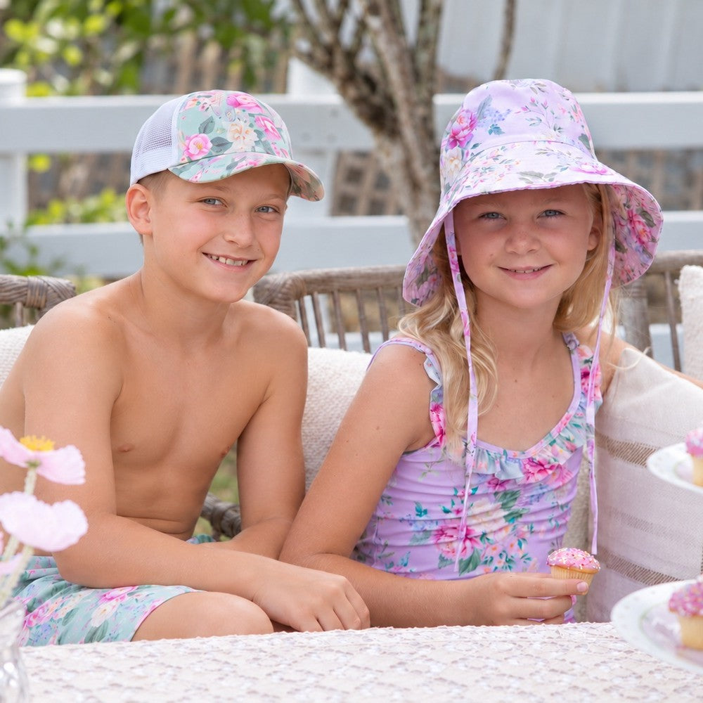 Boy in a floral trucker cap and girl in a Lilienne bucket hat – Olga Valentine kids beach hats and caps