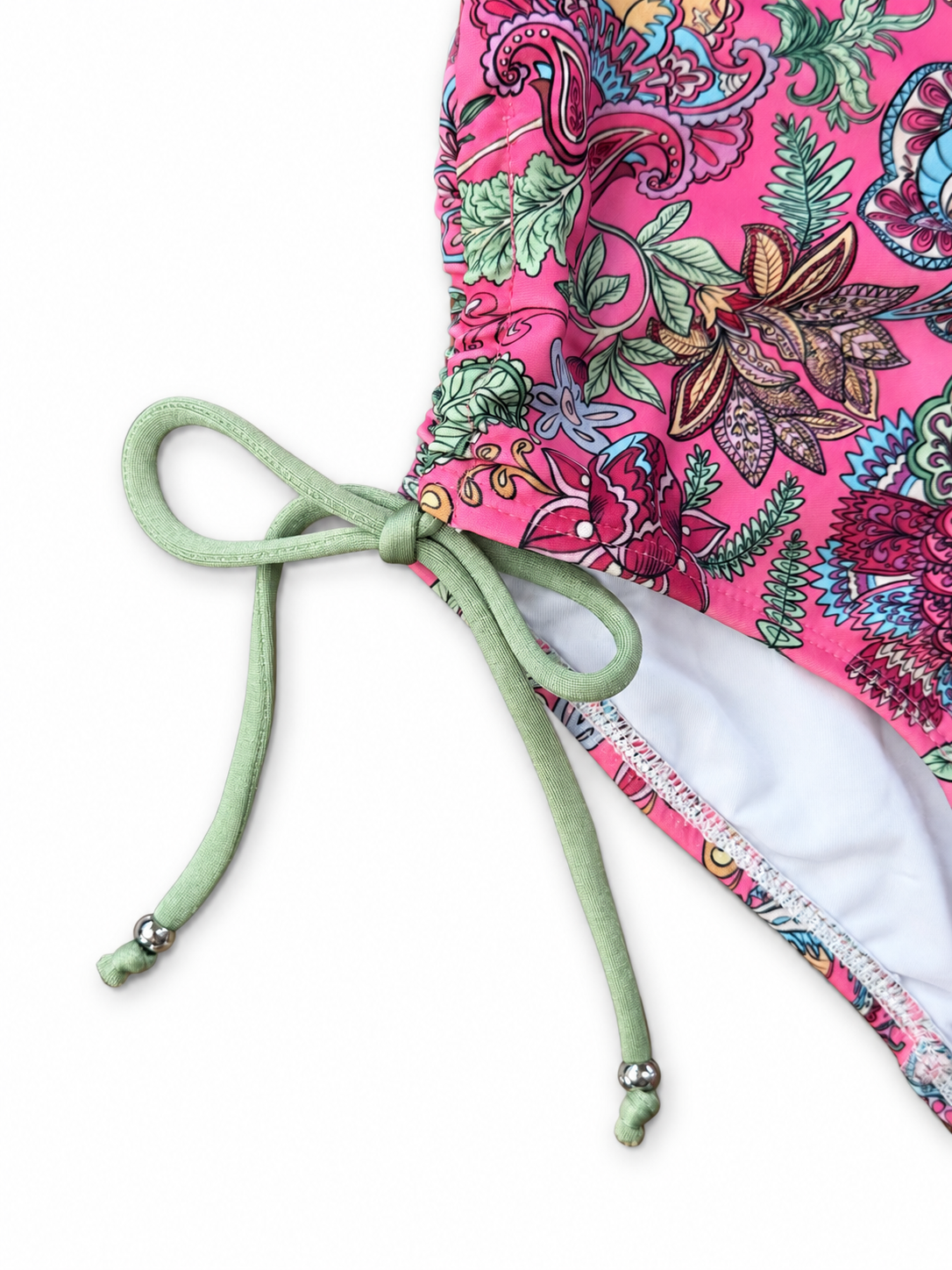 Close-up of a fabric detail with a bright pink floral print, a mint green drawstring tied in a bow. 