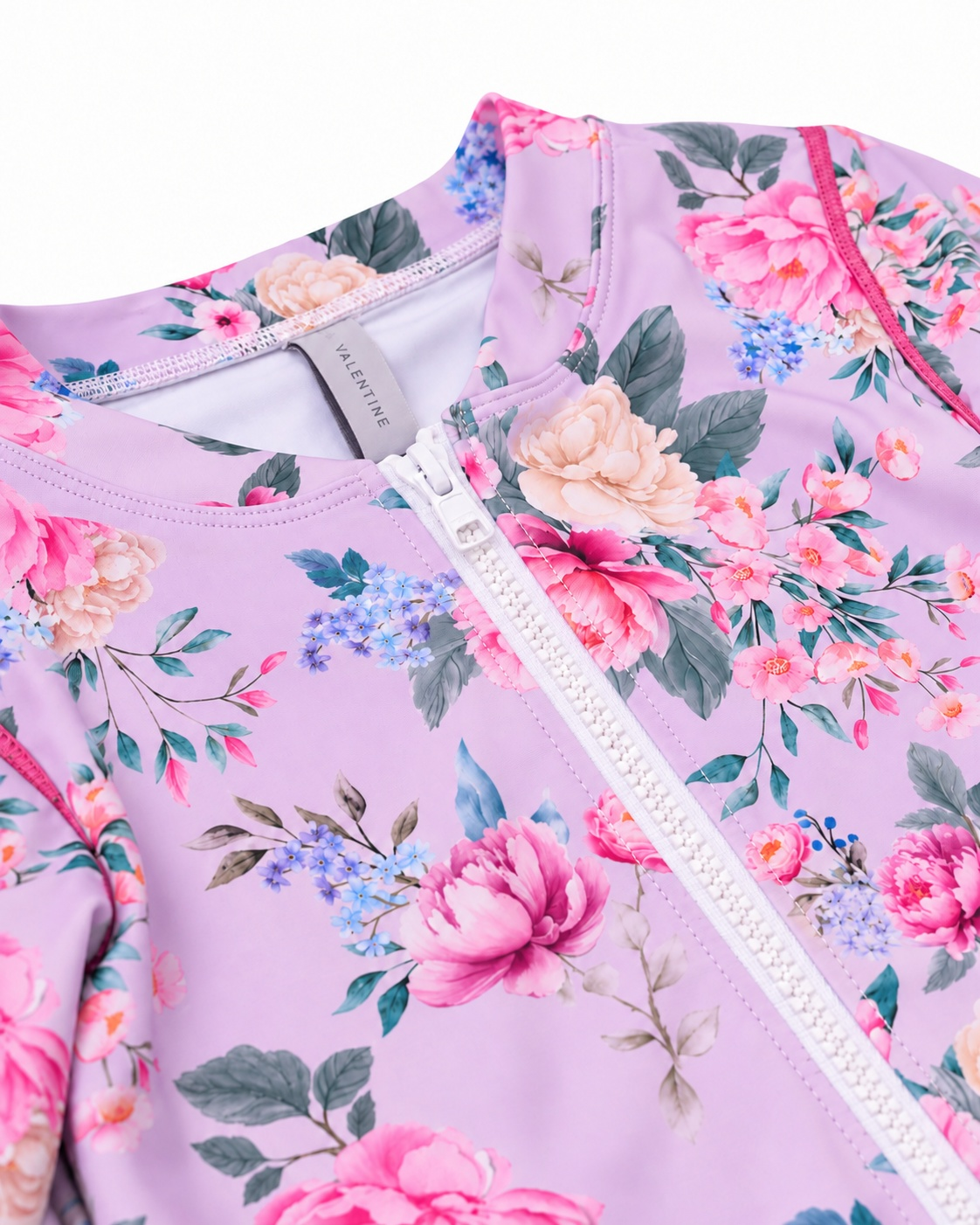 Close-up of the front zip, neckline and Olga Valentine label on the Girls Long Sleeve Zip One Piece in Violetta purple floral print